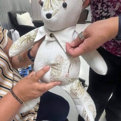 A handmade teddy bear is being passed from one person to another.