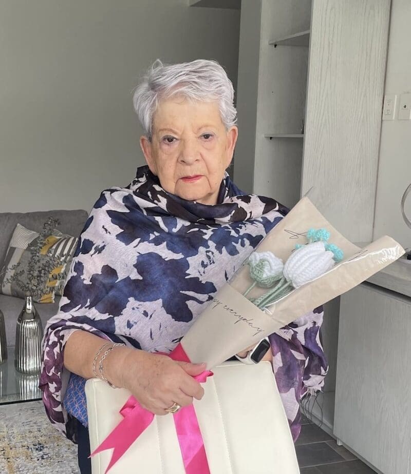 Elderly Woman holding crochet flower bouquet.