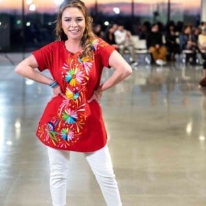 Image of Female Model with a Hand-embroidered-multi-color-Tenango-birds-and-flowers-on-red-cotton-short-sleeve-blouse